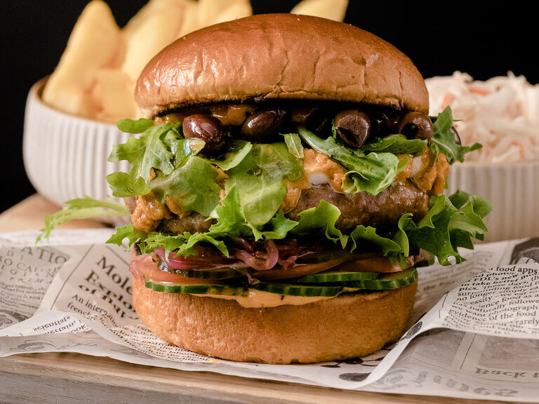 Detailaufnahme eines Gourmetburgers im Restaurant Maerz mit Pommes im Hintergrund